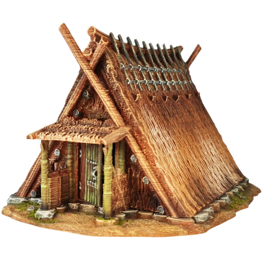 A 28mm scale 3D printed model of a Chigi-Minka, an ancient Japanese dwelling. The structure is characterized by a steep A-frame thatched roof topped with prominent crossed wooden finials (Chigi) and horizontal logs (Katsuogi). It features a sheltered entrance with timber pillars, rustic wooden doors, and a stone-lined foundation, reflecting a high-status or spiritually significant historical residence.