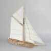 3D printed model of a historical single-mast trading sloop. The ship has a detailed wooden hull, a tall mast with a gaff rig, and sails made of white fabric. The deck shows planking details and railings.
