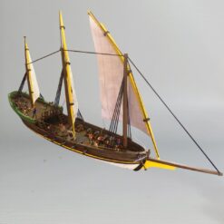 Painted 28mm scale model of a historical Xebec ship, featuring three masts with lateen sails, a wooden deck with cannons, and miniatures for scale.