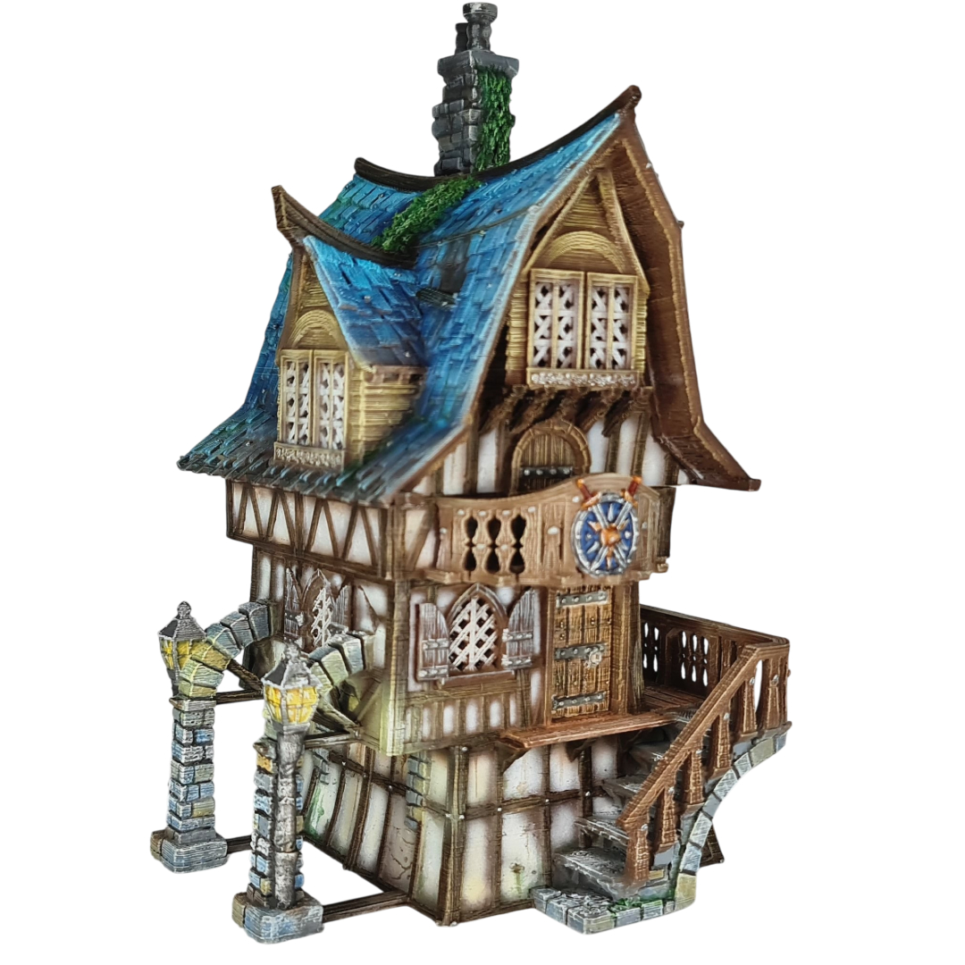 3D printed and painted model of a multi-story medieval fantasy house featuring half-timbered walls, a steep blue roof, stone pillars with lamps, and an external wooden staircase.