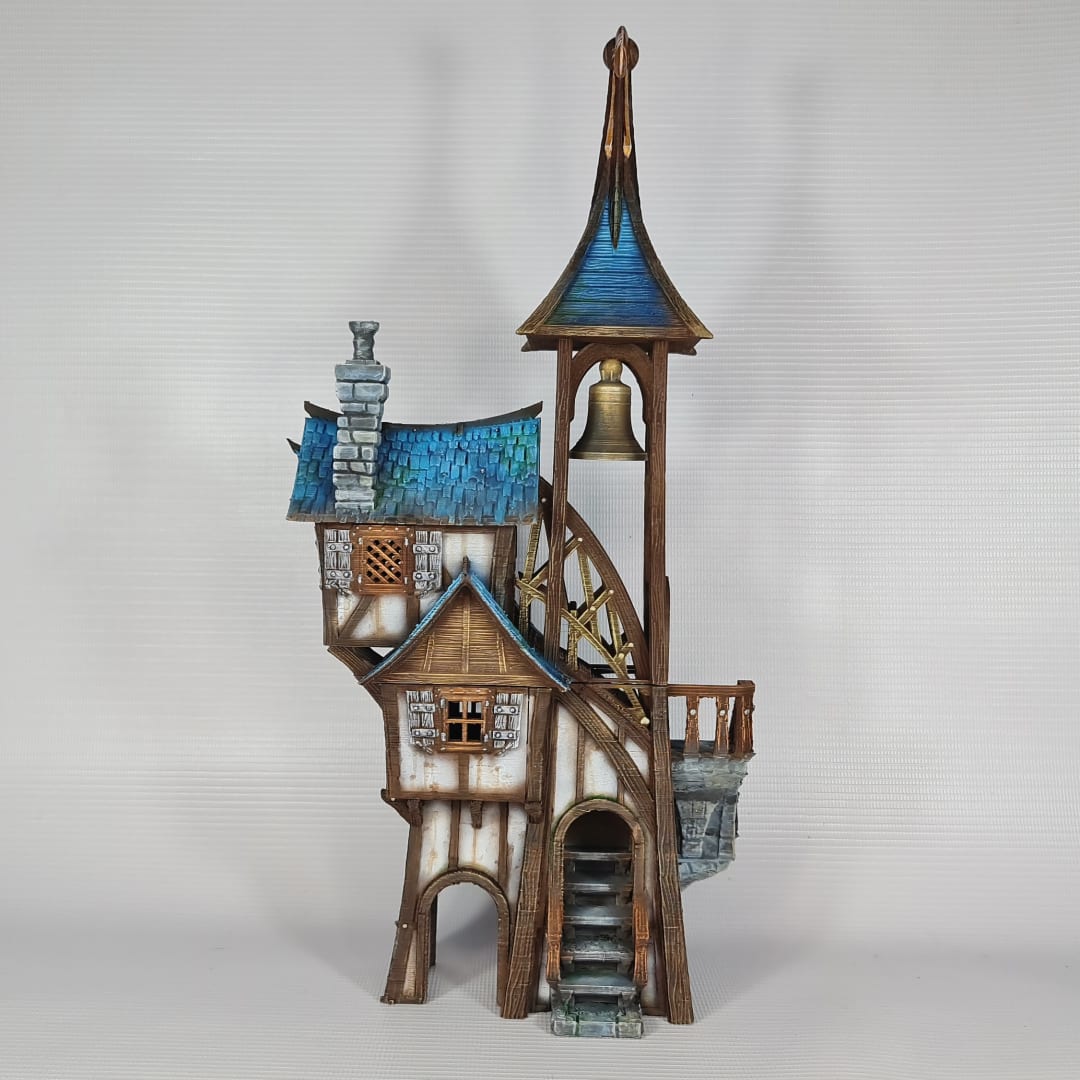 3D printed and painted model of Parson's Lodge, a tall medieval fantasy bell tower with half-timbered walls, blue shingled roofs, stone chimney, and wooden stairs.