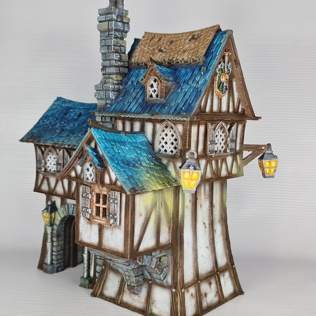 3D printed and painted model of the Oldkeep Barracks, a medieval half-timbered building with blue shingled roofs, hanging lanterns, and wooden textures for tabletop gaming.