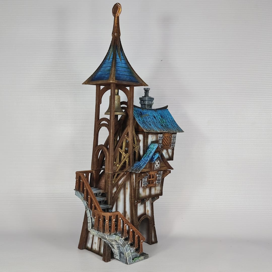 3D printed and painted model of Parson's Lodge, a tall medieval fantasy bell tower with half-timbered walls, blue shingled roofs, stone chimney, and wooden stairs.